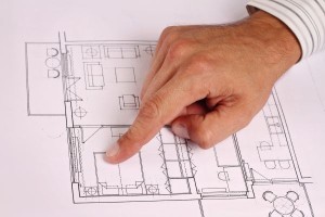 Architect showing project, house plans. Close up on male hand pointing at plan